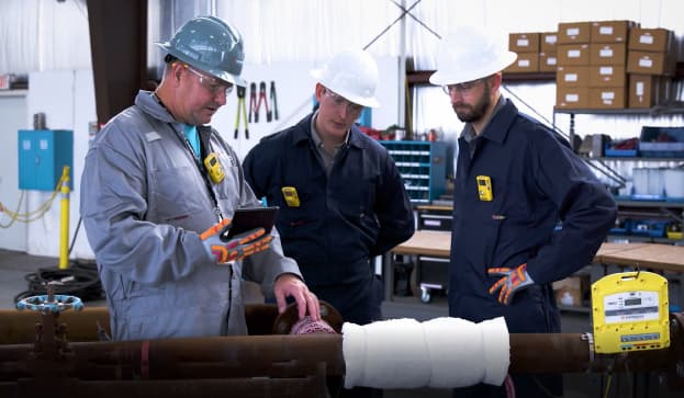 Field technicians reviewing preheat weld treatment and PWHT services on a pipe.